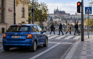 Modré auto zastavilo před přechodem pro chodce na červené na semaforu v Praze.