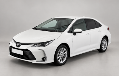 White Toyota Corolla sedan on a light background, front and side view.