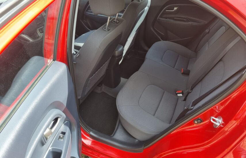 Zadní sedadla vozu Kia Rio s tmavým látkovým čalouněním a bezpečnostními pásy